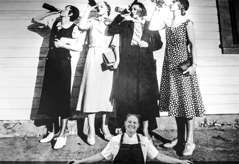 Chef Sarah Wade standing in front of a prohibition era mural of women drinking alcohol